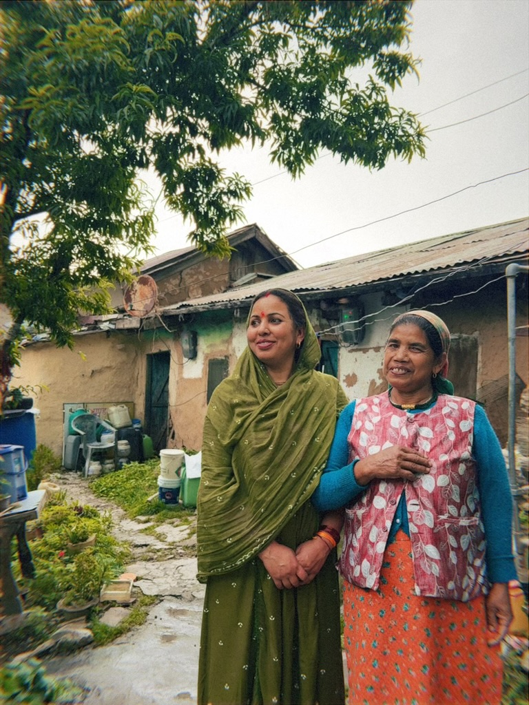 Two women standing together outside their home